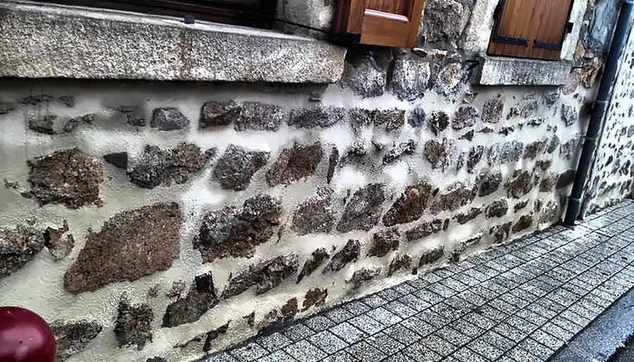 Mur extérieur en pierre avec trace d'humidité remontant du sol par capillarité.